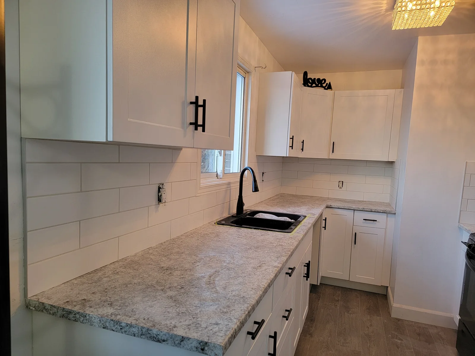 Kitchen with white cabinets, black sink and subway tile backsplash